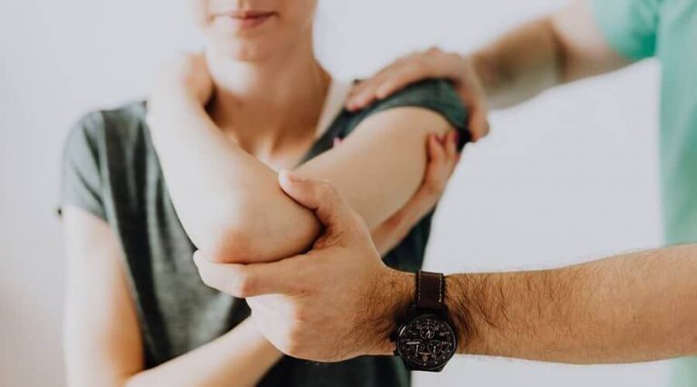 the doctor gives treatment of muscle wasting around the shoulder to a woman