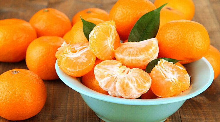 the chopped oranges along with raw oranges were kept in a bowl on the wooden table
