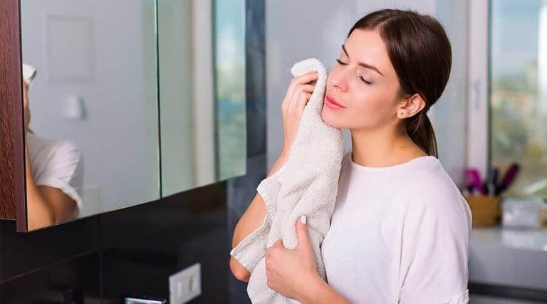 A girl is wiping her face with a towel.