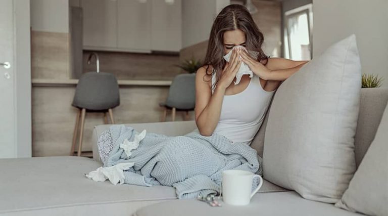 A women sneezing experiencing symptoms of Sinusitis