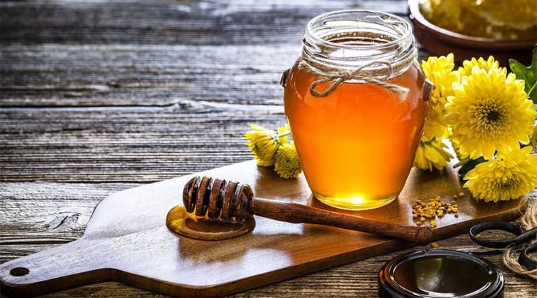 A jar of honey along with flower were kept in a table
