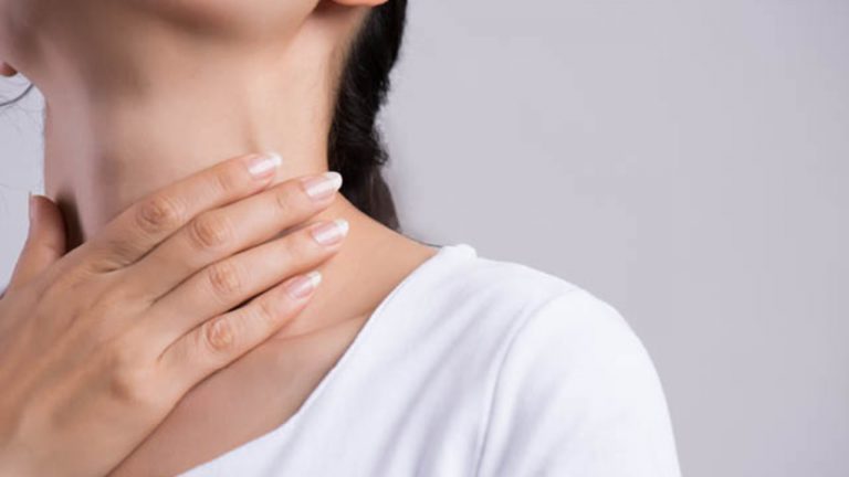 A women holding her neck suffering from thyroid