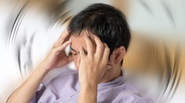 A man holding his head with both hands, appearing distressed, with a blurred swirling effect in the background representing dizziness.