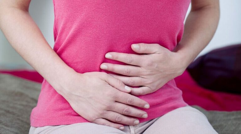 A woman holding her stomach and experiencing bloating in her stomach
