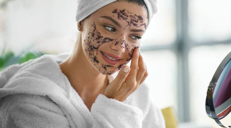 A girl standing in front of a mirror, carefully applying cream to her face as part of her skincare routine