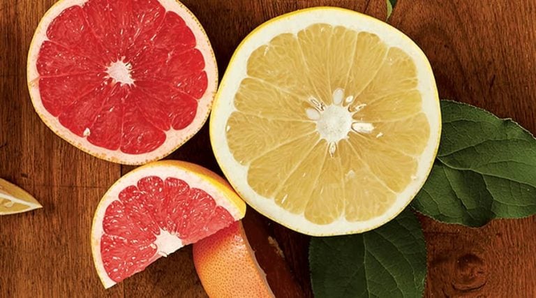 Sliced grapefruits are placed on a wooden table.