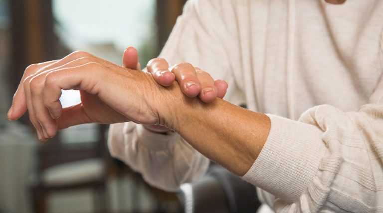 old woman rubbing her arm with her hand