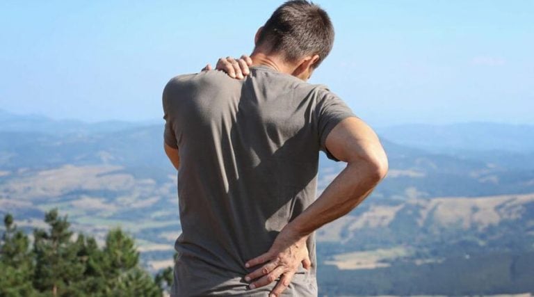 a man holding his back and shoulder while showing his back