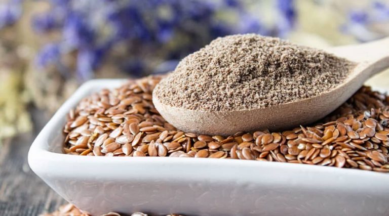 a scoop of powder placed on a bowl filled with flaxseeds