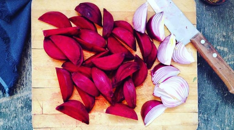 chopped onions and beetroot with knife placed on wooden chopping board