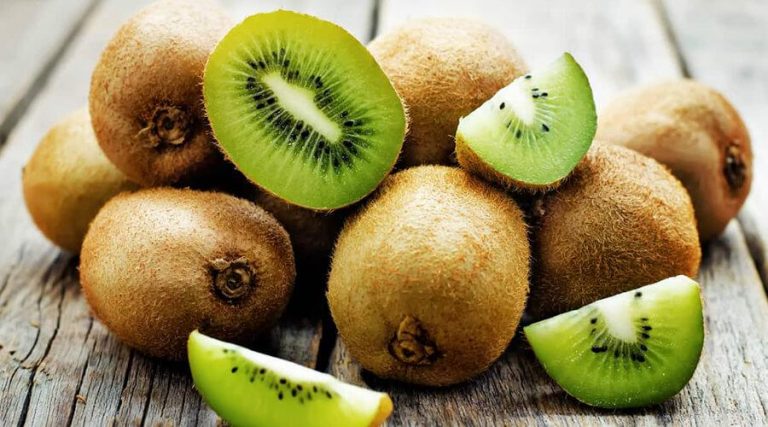 raw and sliced kiwi placed on a wooden table