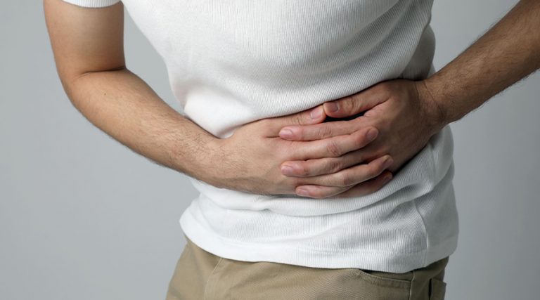 a man holding his stomach because of kidney pain