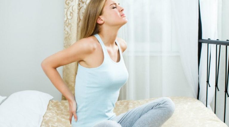 a young women holding her back in pain