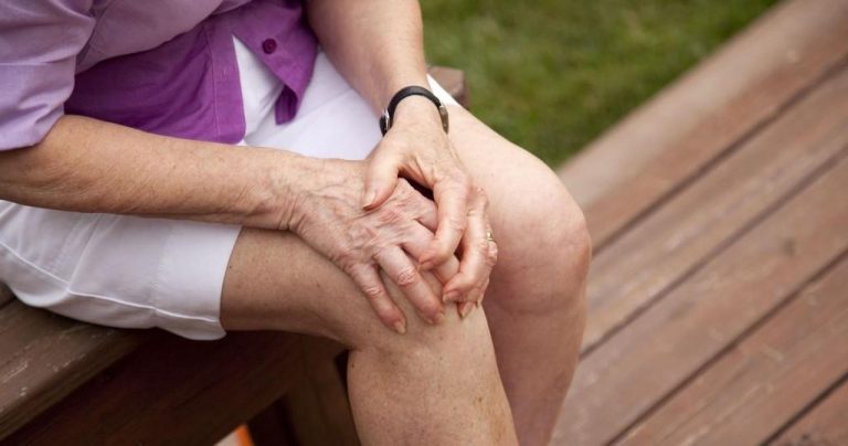 an old lady holding her knee in pain
