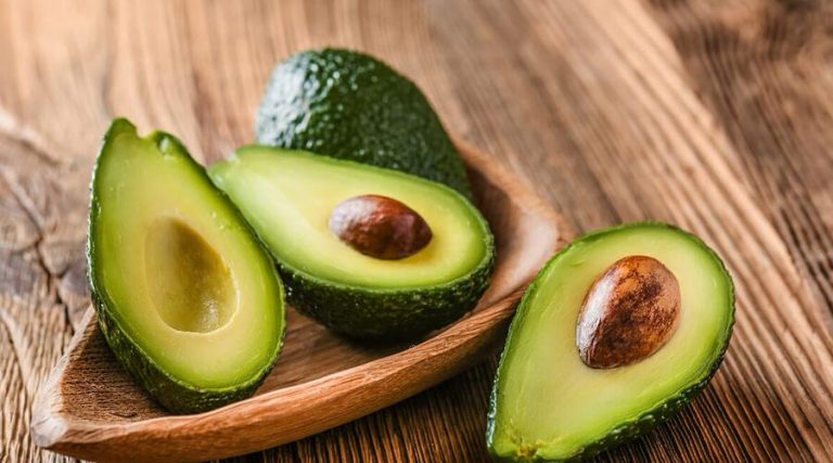 avocado sliced in half, placed on a wooden table