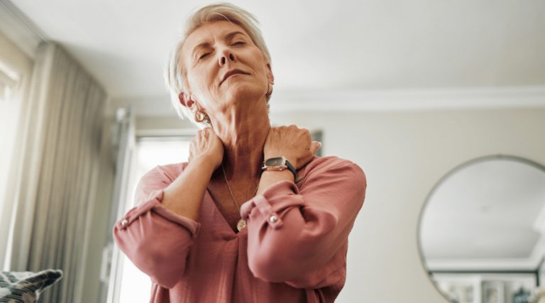old women holding her shoulder with both hands in pain