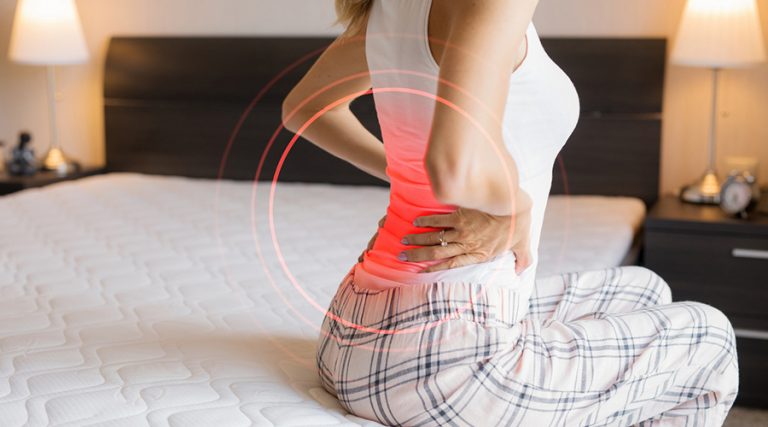 young lady holding her hands on the lower back in pain