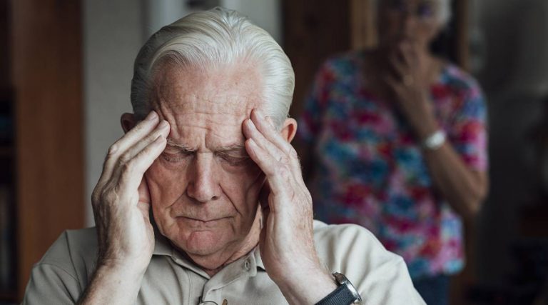 old man holding his head in pain
