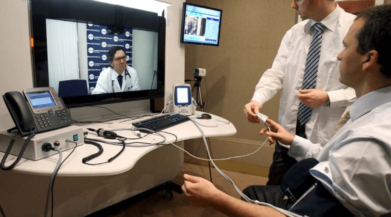 A telemedicine consultation setup where a patient is seated in a clinical environment, connected to medical devices for remote health monitoring