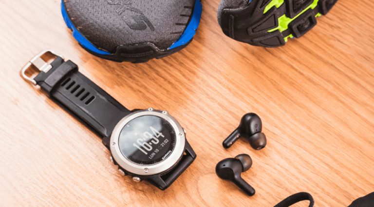 a picture of smartwatch and wireless earphones placed on a wooden table