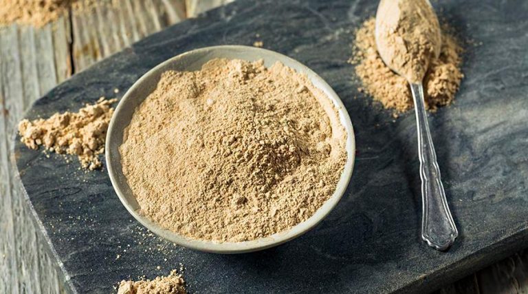 a bowl and spoon filled with maca powder