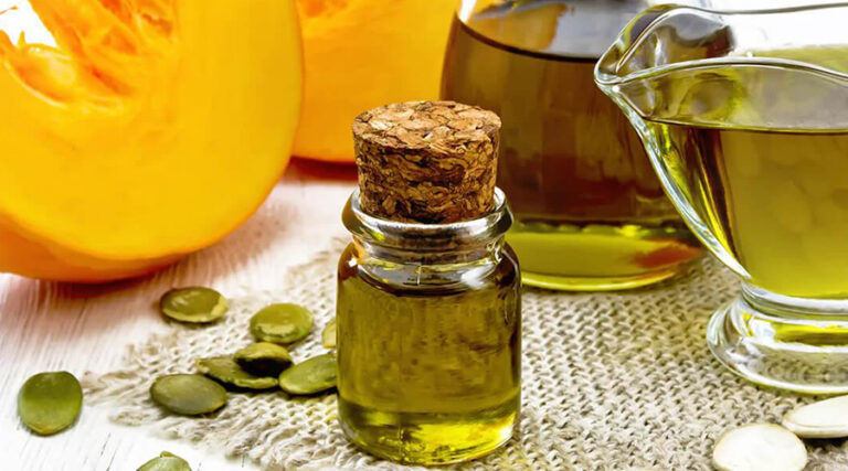 bottle of pumpkin seed oil placed on a table next to pumpkin seeds